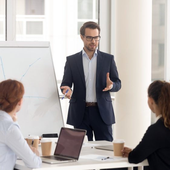 Male,Business,Coach,Speaker,In,Suit,Give,Flipchart,Presentation,,Speaker